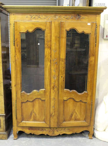 A 19th century French cherry wood armoire, the moulded pediment above a pair of glazed and