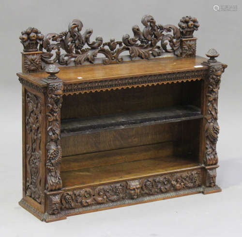 A late Victorian Continental oak dwarf bookcase with carved masks and foliate scrolls, the open