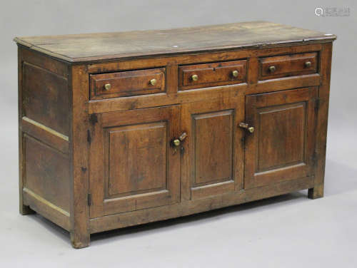 An 18th century oak dresser base, fitted with three frieze drawers above cupboards, on block legs,