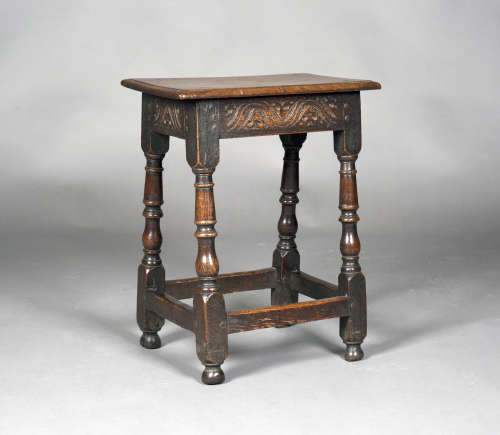 A late 17th century oak joint stool with a carved foliate frieze, on turned and block legs, height