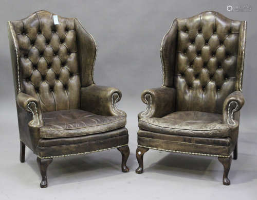 A pair of 20th century George III style brown leather wingback armchairs with brass studwork