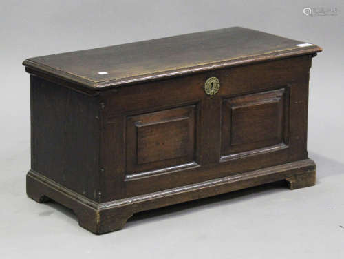 A small 18th panelled oak coffer, the hinged lid above a double-panel front, raised on shaped