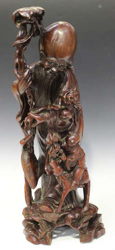 A large Chinese carved hardwood figure group of Shoulao and a boy acolyte, seated on the back of a