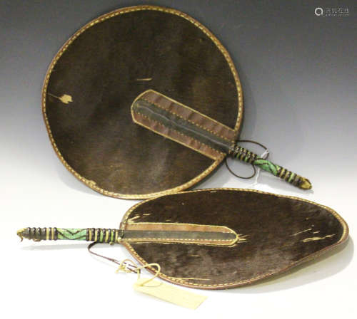 A pair of late 19th/early 20th century Zulu animal hide circular fans, the handles bound in leather,