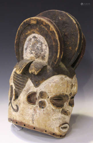 An African carved and painted wooden double-sided helmet mask, modelled with a triple-finned