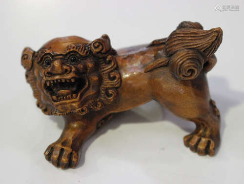 A Japanese boxwood netsuke, 20th century, carved in the form of a playful shishi, incised two-