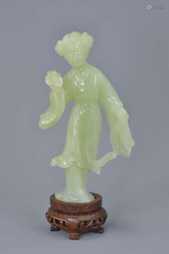 A Chinese carved celadon jade figure of a girl on wooden stand. 14cm tall
