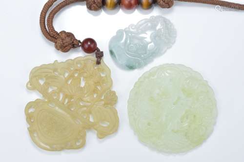 A Chinese carved jadeite deer pendant together with a pale celadon jade dragon pendant and one other