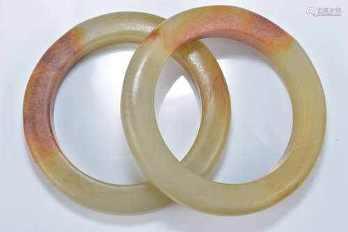 Two Chinese celadon and brown jade bangles. 8.5cm diameter. Inner diameter 6cm.