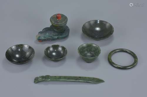 A group of seven Chinese jade items including a pot and cover on stand, a bangle, three dishes, a cu