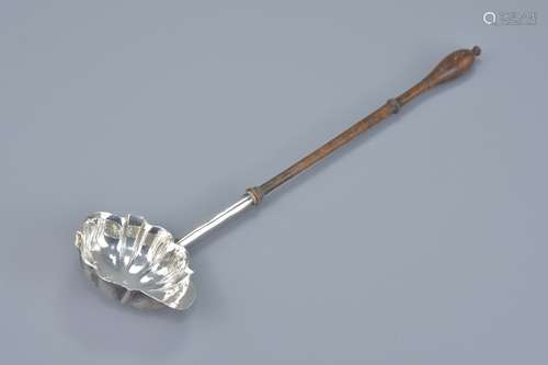 A Georgian George III Silver ladle with turned wood handle. London 1767. Maker D M. Length 33cm.