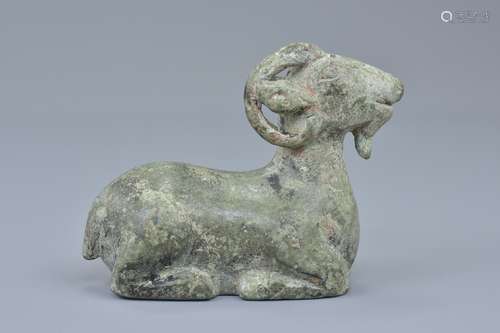 A Chinese Han dynasty or later cast bronze figure of a recumbent ram with it's legs tucked under its