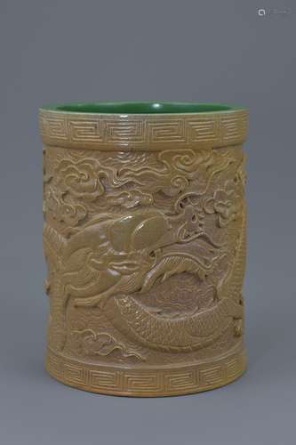 A Chinese porcelain brush pot carved with five claw dragon amongst clouds with green interior and ba