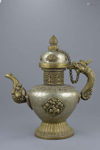 A large Tibetan brass ewer and cover with linked chain heavily decorated with repousse work and pane