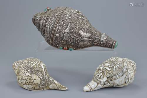 A large Tibetan Buddhist hammered white metal conch shell trumpet with raised decoration and coloure