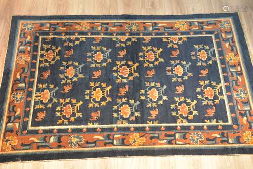 A Tibetan / Chinese 19th century blue ground rug woven with orange and tan border decorated with bat