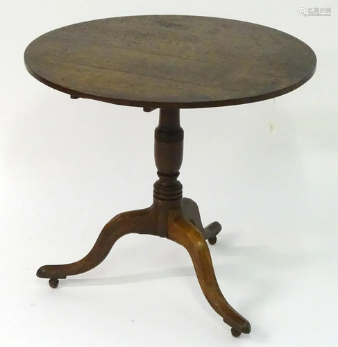 A Georgian oak tilt top table with a circular top above