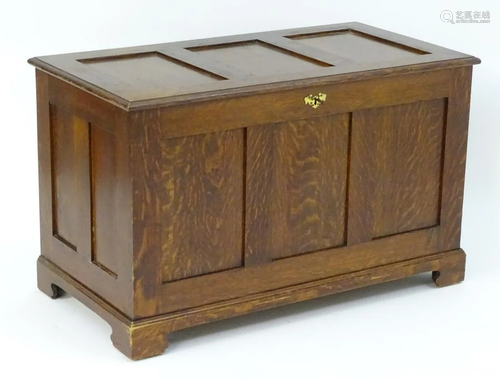 A late 20thC oak coffer with a three panelled top and