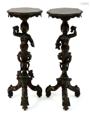 A pair of 19thC walnut stands in the form of cherubs,