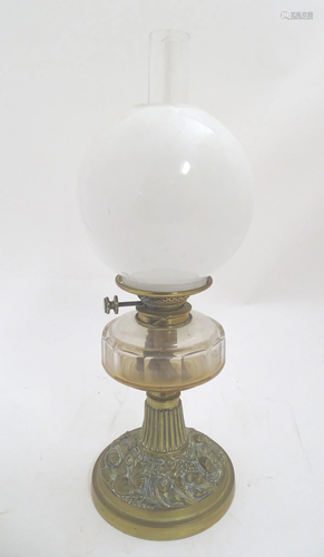 A Victorian oil lamp with a brass base decorated …