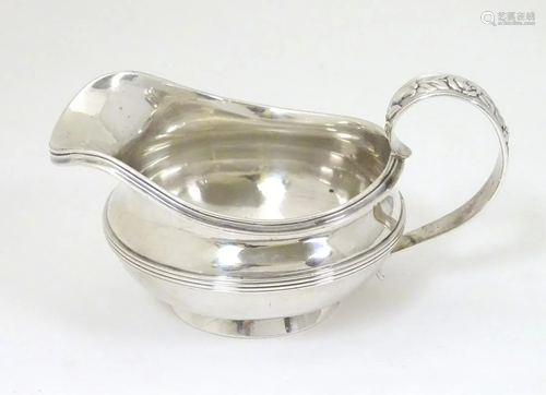 A silver jug / sauce boat with floral decoration to