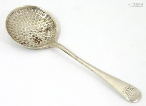 A silver preserve spoon with hammered decoration.