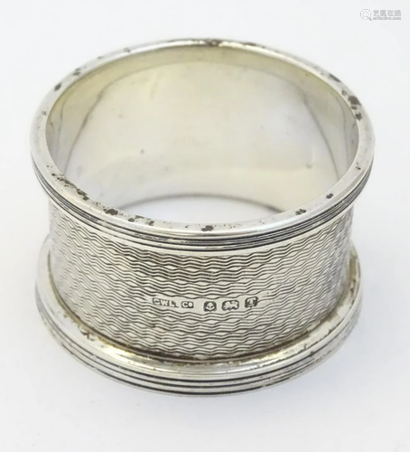 An Art Deco silver napkin ring with engine turned