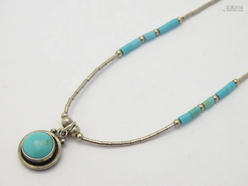 A silver necklace set with turquoise detail in the Z…