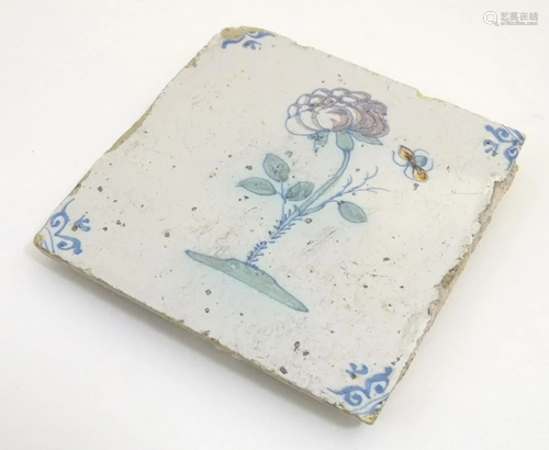 A 17thC Delft tile depicting a flower and a flying