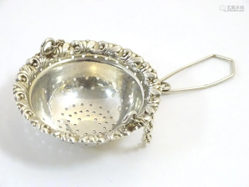 A silver tea strainer with spout hanging attachme…