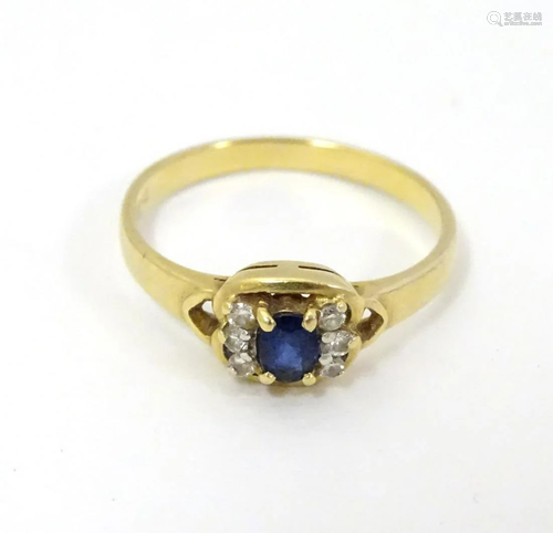 An 18ct gold ring set with sapphire flanked by dia…