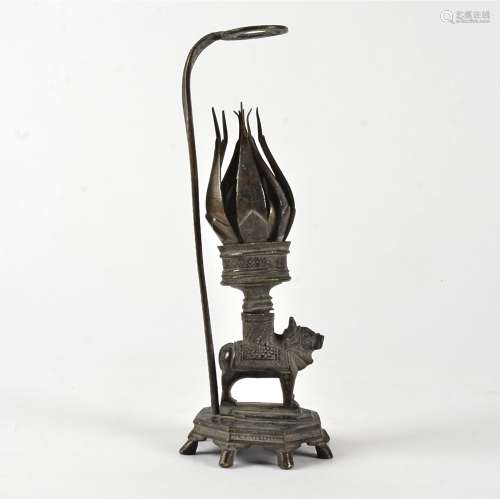 An Indian brass candlestick holder and snuffer, raised on an octagonal base, upon the back of a