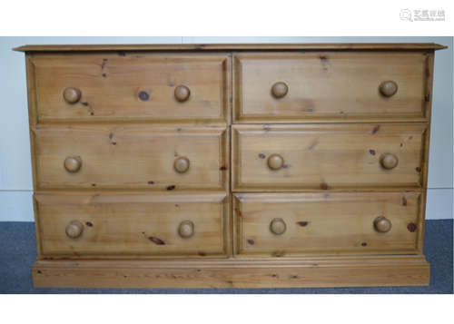 A contemporary pine chest of drawers, comprising of six short drawers, moulded top raised on a