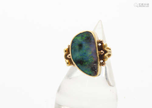A continental black opal and yellow metal dress ring, the large oval shaped polished opal within a