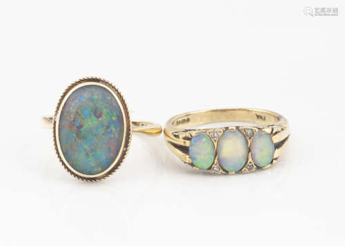 A 9ct gold three stone precious opal dress ring, the three oval cabochons alternatley set with eight