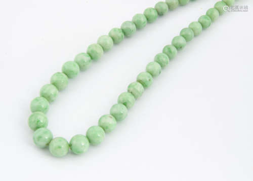 A graduated string of jade beads, the spherical polished beads united by a heavy white metal