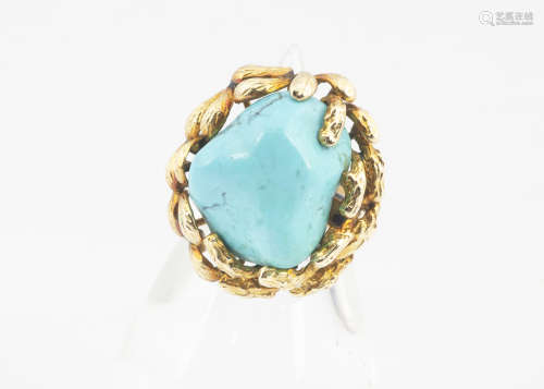 A continental yellow metal and turquoise dress ring, the boulder stone in a textured organic style