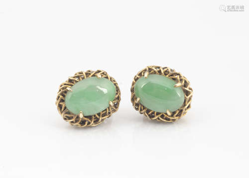 A pair of cabochon jade and 18k marked ear studs, the claw set jade centres in a basket oval mount