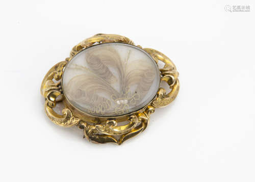 A 19th Century mourning brooch, the yellow metal surround centred with a plaited hair and gilt