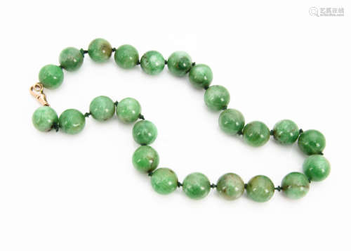 A green jade bead necklace, the knotted, strung spheres with gold clasp, each bead approximately