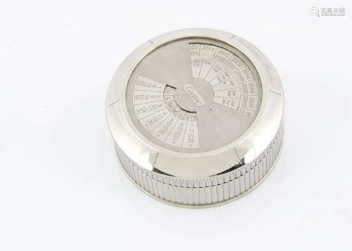 A modern silver plated perpetual desk calander by Cartier, circular with fluted sides, rotating