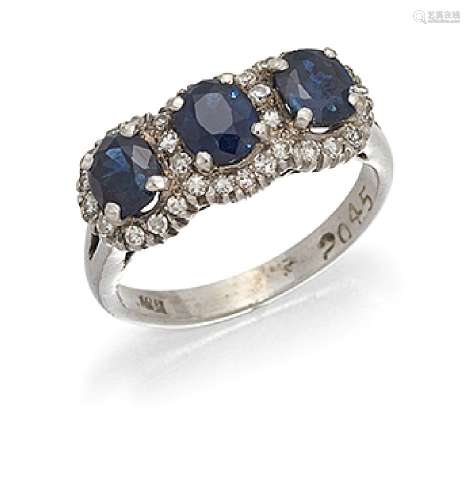 A diamond and sapphire ring, the three claw-set cushion-cut sapphires within a single-cut diamond