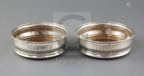 A pair of George III silver wine coasters by Soloman Hougham, the central boss engraved with a