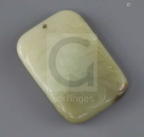 A Chinese pale celadon and brown jade plaque, 19th century, carved in relief with a dragon and