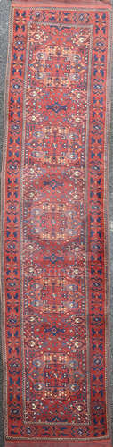 An Ersari red ground runner, with shaped polygons in a field of geometric motifs, 13ft by 3ft 6in.