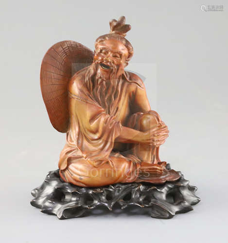 A Chinese boxwood seated figure of a fisherman, with hongmu stand, c.1900, the fisherman with