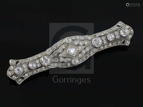 A 1920's pierced platinum? and millegrain set diamond bar brooch, set with round cut stones, the