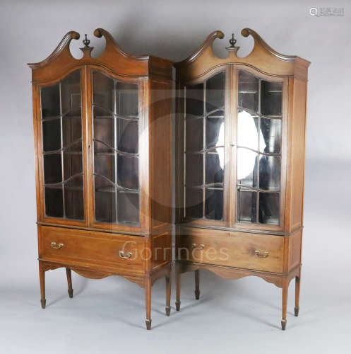 A near pair of Edwardian satinwood banded mahogany bookcases, with swan neck pediments and