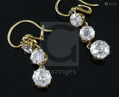 A pair of gold and graduated three stone diamond set drop earrings, the largest stone on each drop