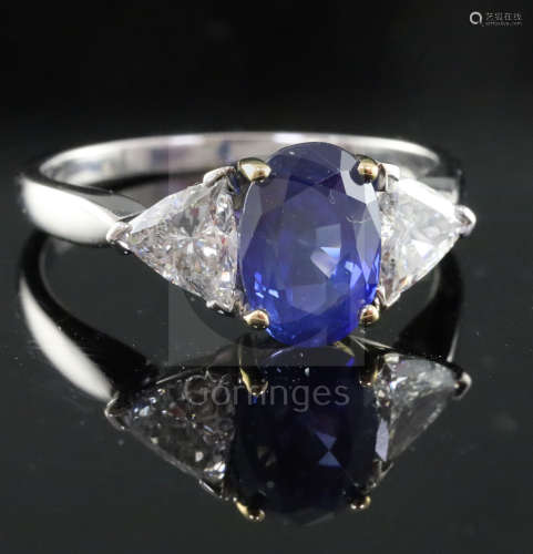 A modern 18ct white gold sapphire and diamond three stone dress ring, the oval cut sapphire weighing
